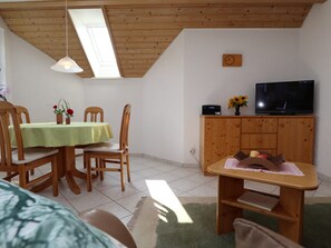 Une pièce comprenant une table à manger, des chaises, un téléviseur et un meuble.