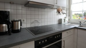 Una cocina moderna con una placa de inducción negra, una cafetera y un hervidor.