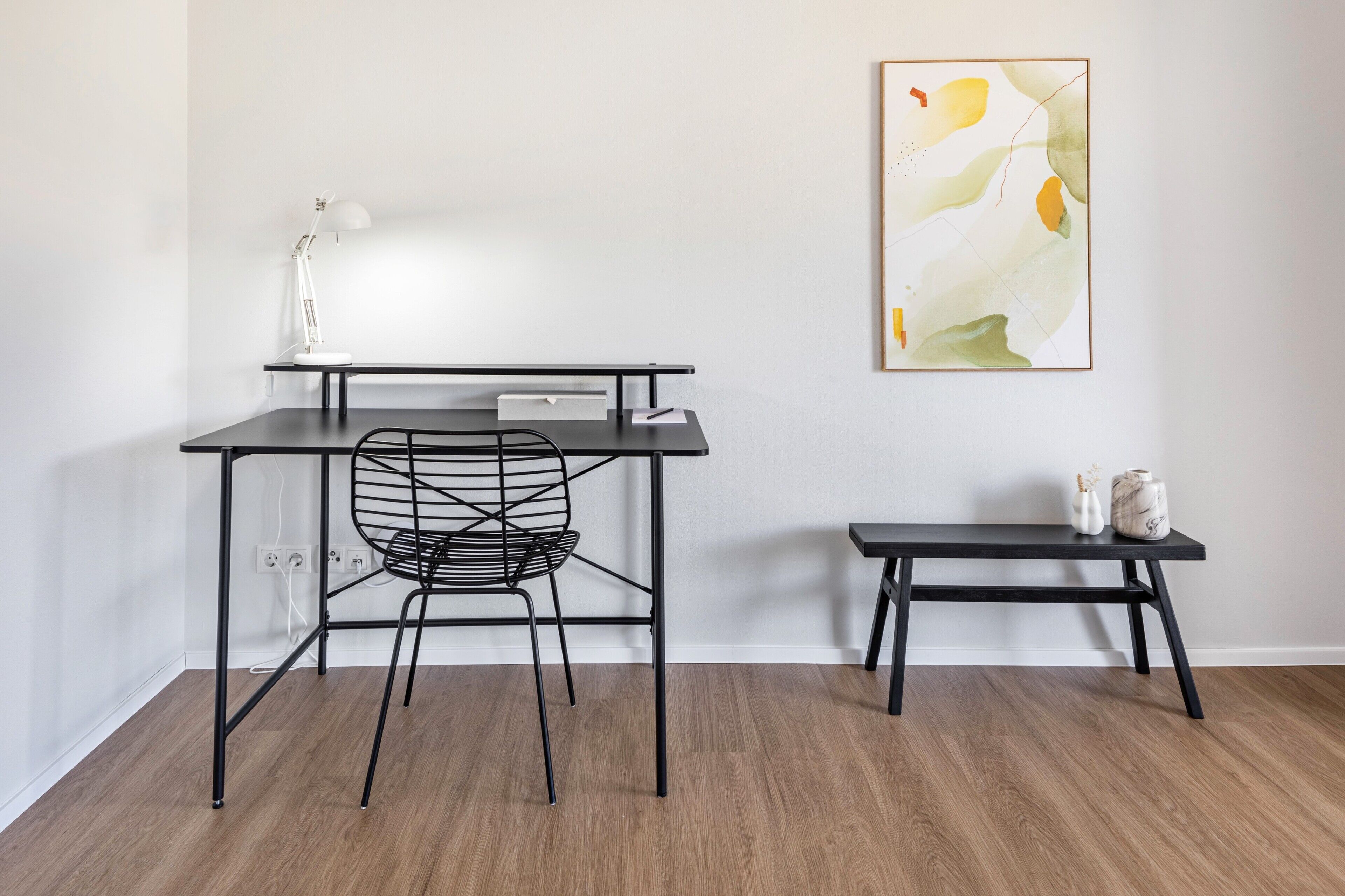 A modern workspace with a desk, chair, and a small bench.