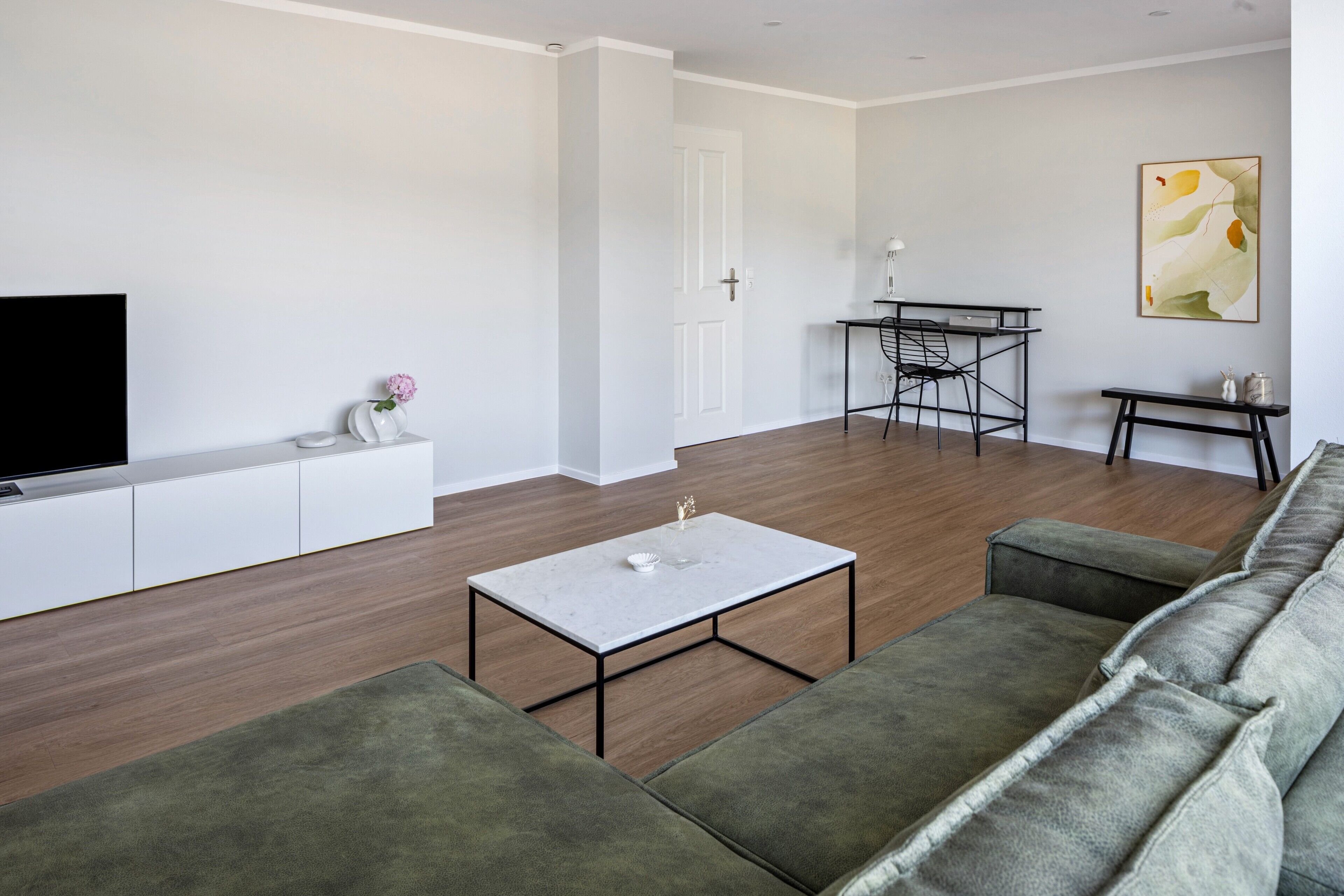 Ein modernes Wohnzimmer mit einer Couch, einem Couchtisch, einem Fernseher und einem Essbereich mit Tisch und Stühlen.