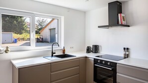 A modern kitchen with a window, a built-in oven, and a black range hood.