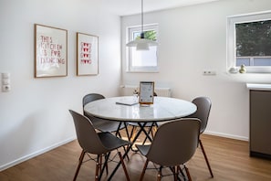 Uma cozinha moderna com uma mesa de jantar redonda, cadeiras e duas frases emolduradas na parede.