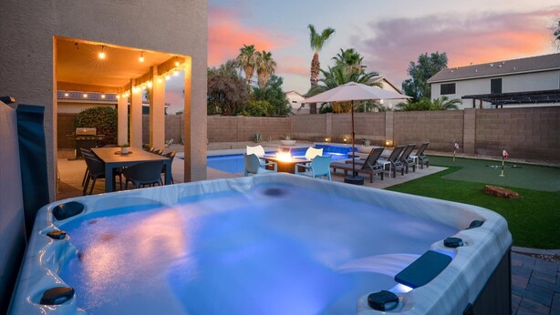 A backyard with a hot tub, outdoor seating, a pool, and a patio area. - Desert Playhouse | Pool & Hot Tub • Arcade • Golf (Chandler)