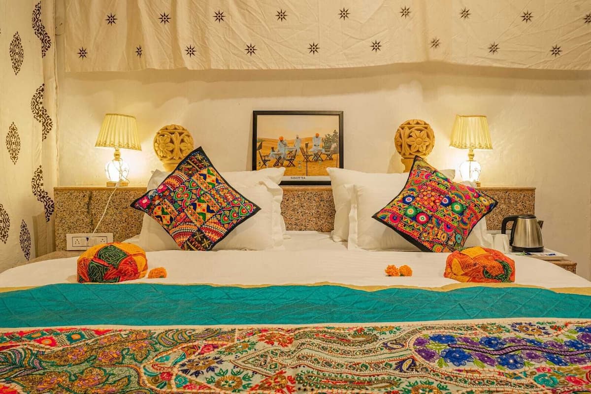 Une chambre d’hôtel avec un grand lit, deux tables de chevet, un tableau encadré au mur et des coussins décoratifs.