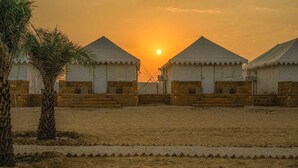 Een rij eenvoudige, gelijkvloerse gebouwen met platte daken, in een rij geplaatst met zand eromheen.
