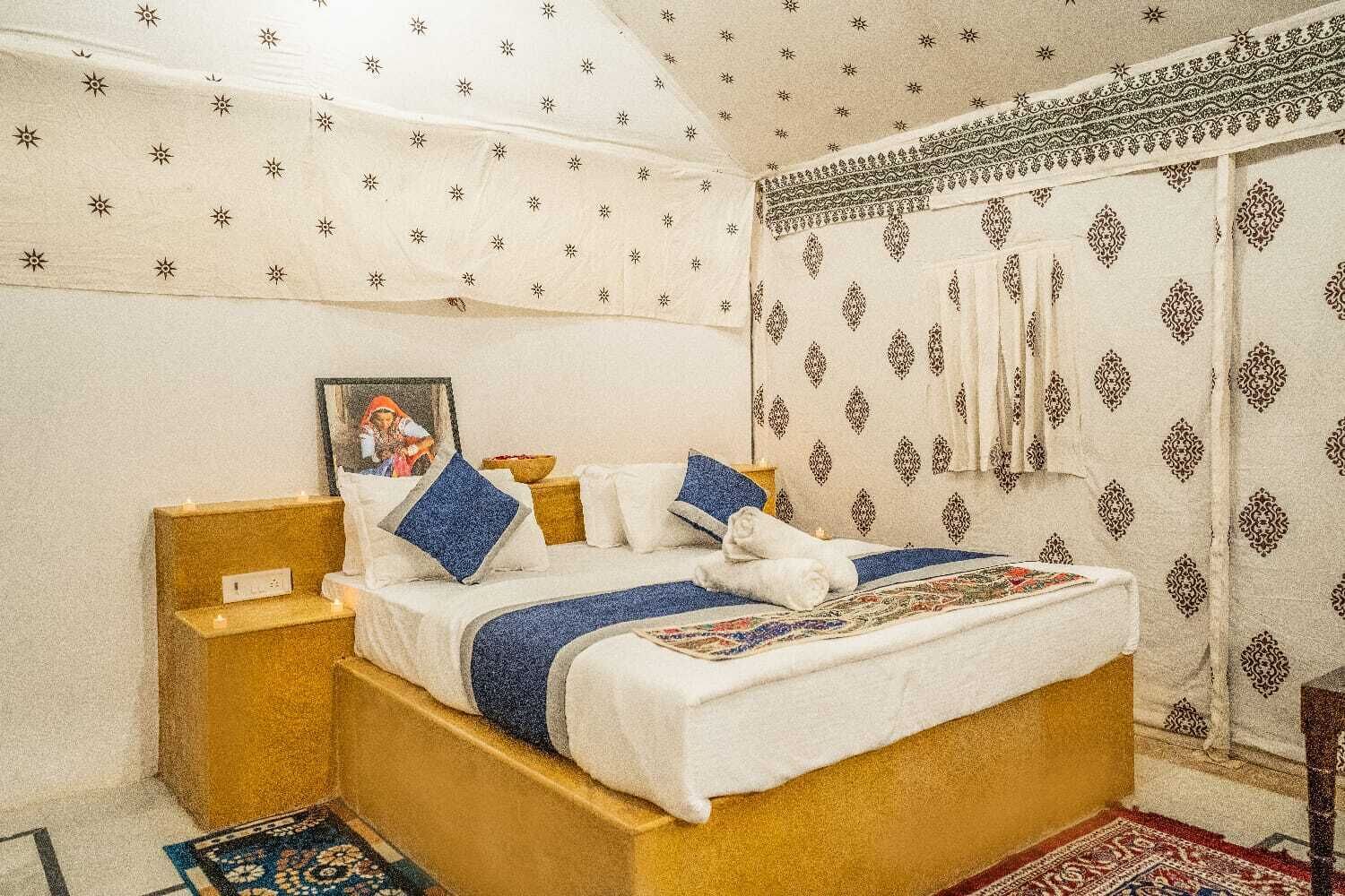 A bedroom with a bed, nightstands, a framed picture, and patterned curtains.