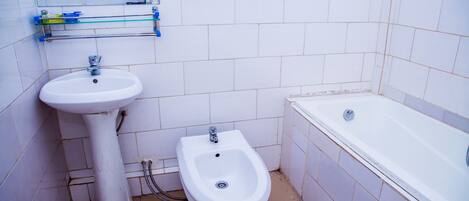 Un baño con lavamanos pedestal, bidé y bañera.