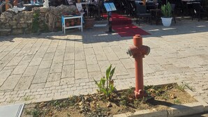 An outdoor patio area with tables and chairs, a red carpet, and a stone wall. - Güven hotel (Manavgat)