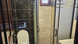 A modern bathroom with a toilet, shower, and sink. - Güven hotel (Manavgat)