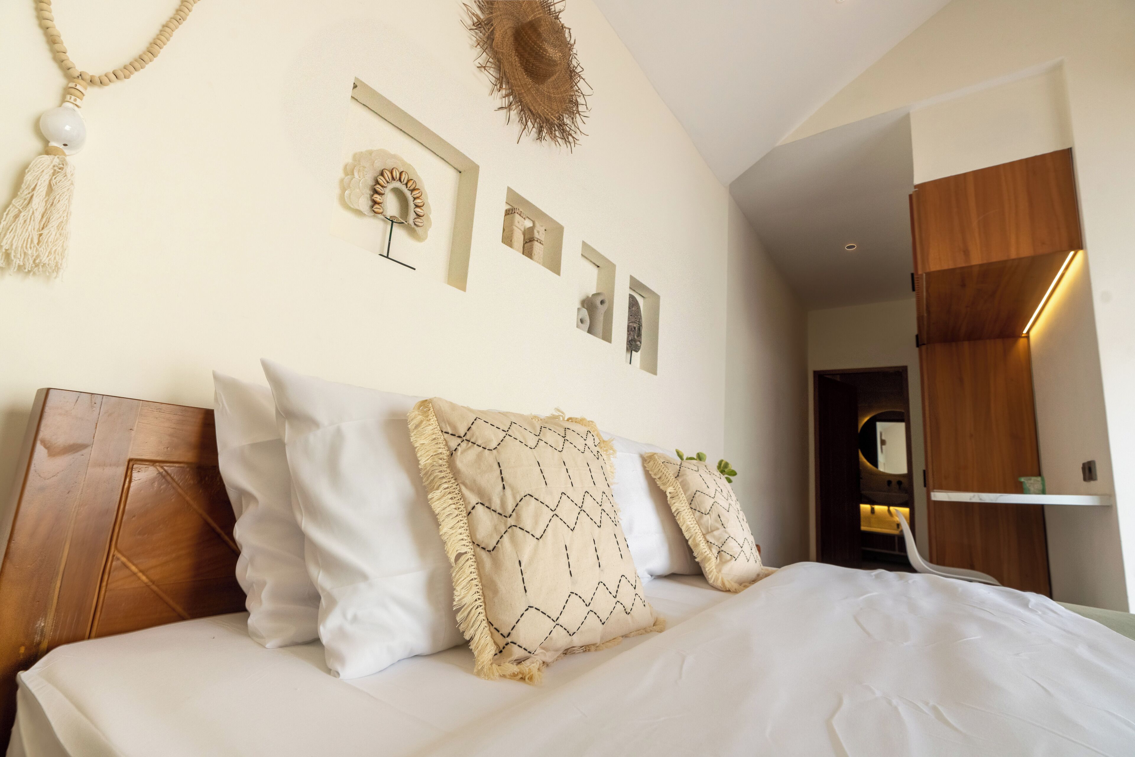 Quarto bem organizado com cama, almofadas e decoração de parede.