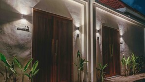 A building with two wooden doors, each with a small sign above. There are plants placed in front of the doors. - Senna Villa (Munggu)