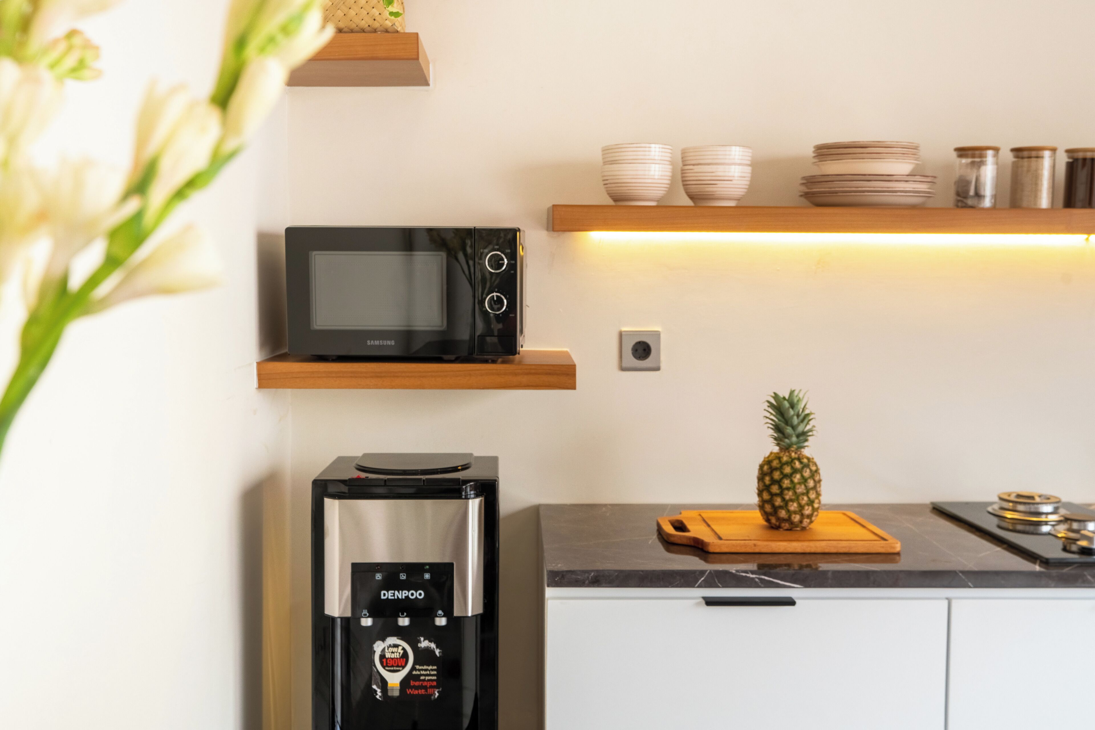 Una cocina con microondas, dispensador de agua y una piña sobre la encimera.