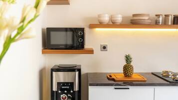 Una cocina con microondas, dispensador de agua y una piña sobre la encimera.
