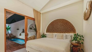 A bedroom with a large bed, a round woven headboard, a small round table, and a potted plant. - Senna Villa (Munggu)