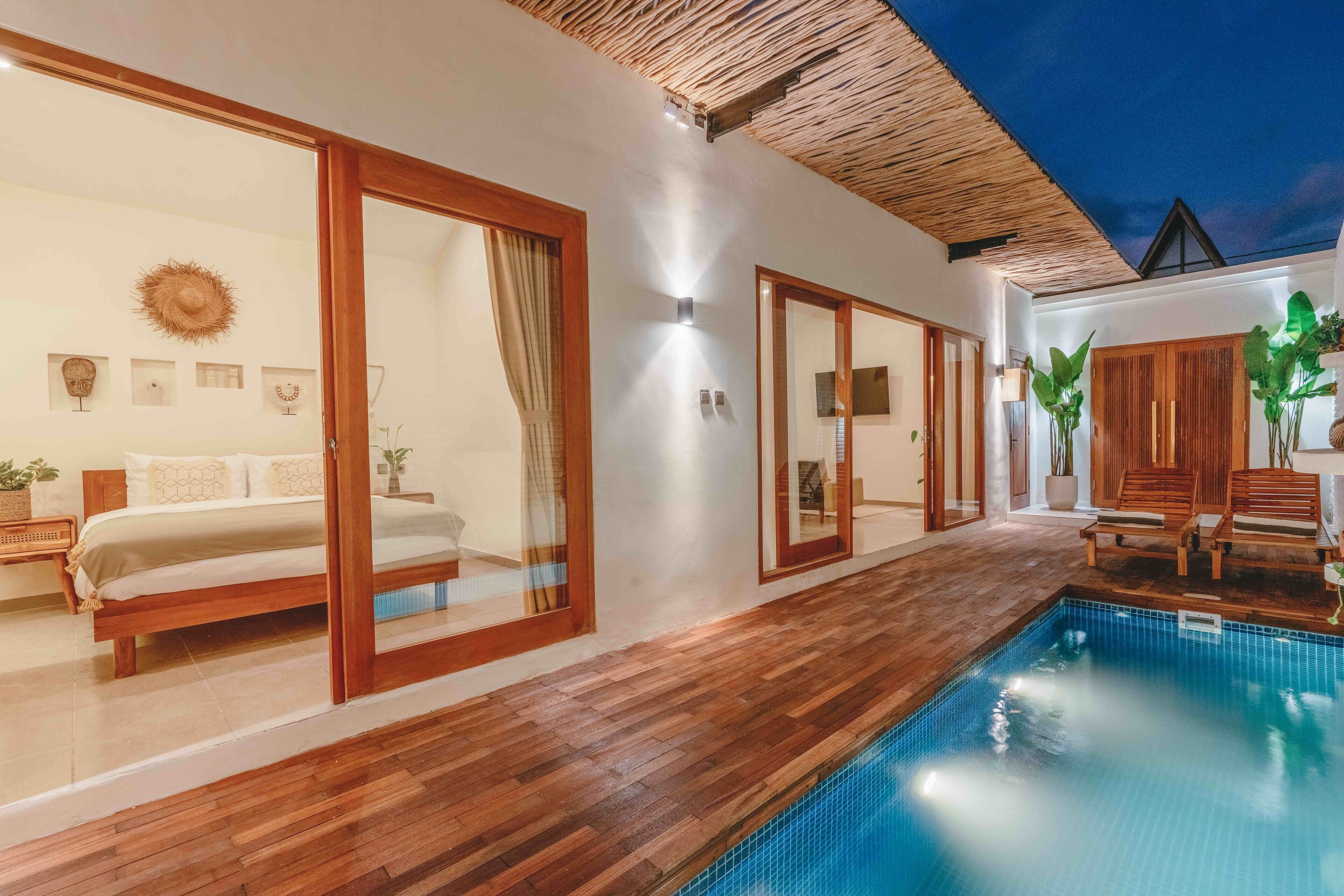 A modern hotel room with a wooden floor, a large bed, a private balcony, and a pool area. - Senna Villa (Munggu)