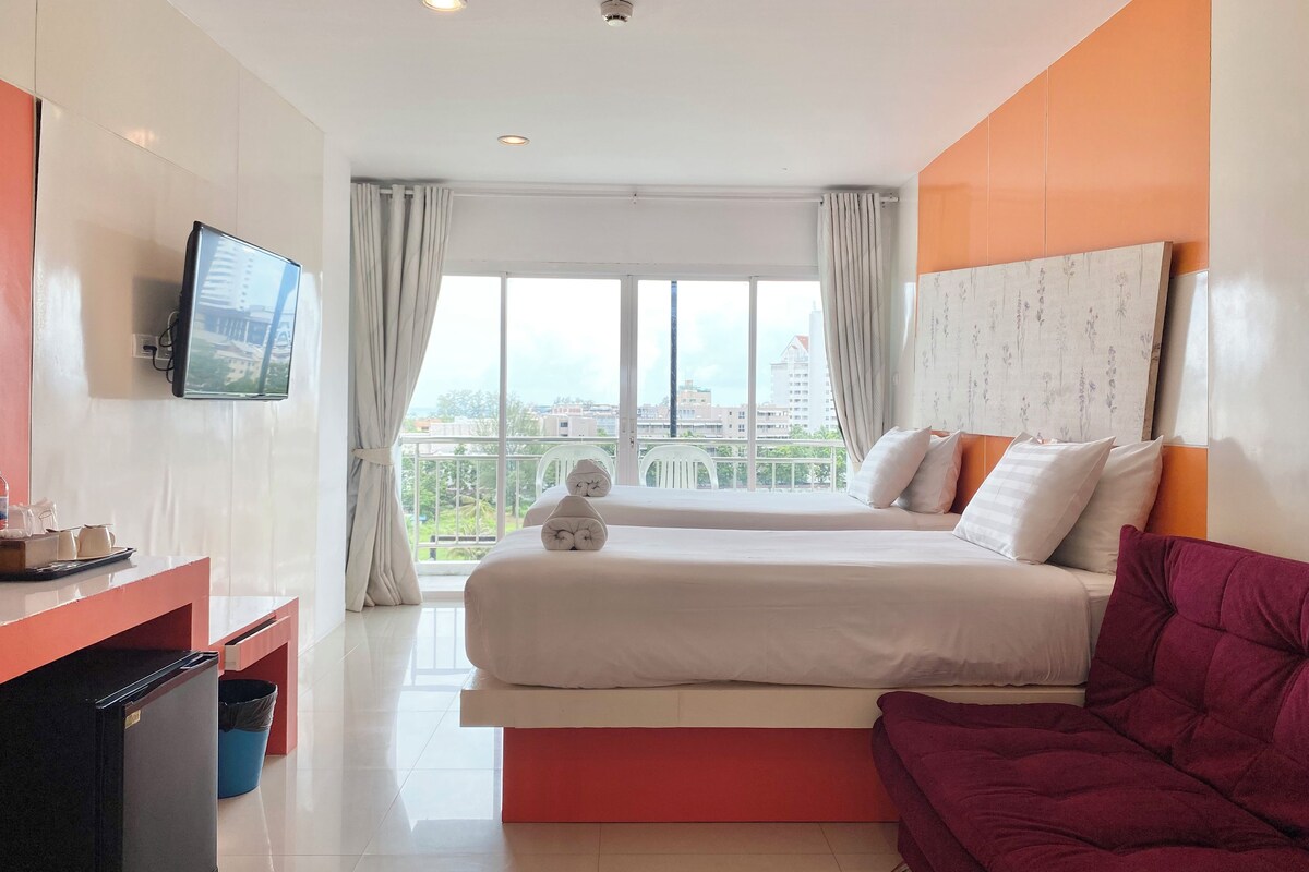 A hotel room with a bed, a TV, a desk, and a balcony with a view.
