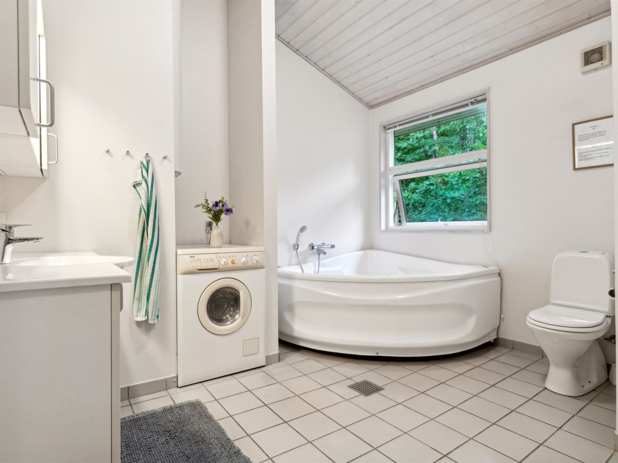Un baño moderno con lavadora integrada, una bañera independiente y un inodoro.