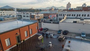 A rooftop parking area with several cars, a few potted plants, and a bench. - Stay Roanoke | Walkable Downtown Rooftop Apt (Roanoke)