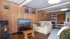 Ein gemütliches Wohnzimmer mit Kamin, Fernseher, Sofa und einer Holzwand.