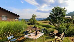Ein Sitzbereich im Freien mit Tisch, Stühlen und einer Weinflasche, vor dem Hintergrund eines Hauses und einer schönen Landschaft.