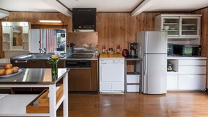 Eine moderne Küche mit Holzschränken, Edelstahlgeräten und einer zentralen Kochinsel mit Spüle und Obstschale.
