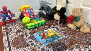 Verschiedene Kinderspielzeuge und ein Malbuch auf einem gemusterten Teppich.