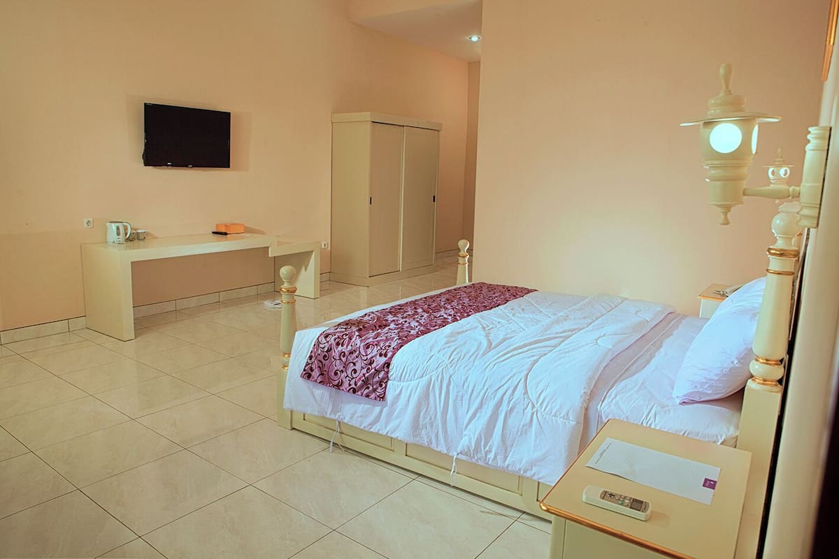 A bedroom with a bed, bedside table, and a television on the wall.