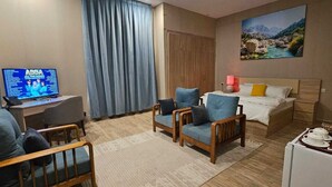 A hotel room with a bed, a desk with a computer, a chair, a coffee maker, and a painting on the wall. - Sugardunes Resort (Al Khaluf)