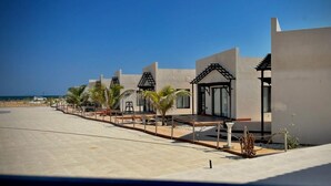 A modern resort with multiple buildings, a pool area, and palm trees. - Sugardunes Resort (Al Khaluf)