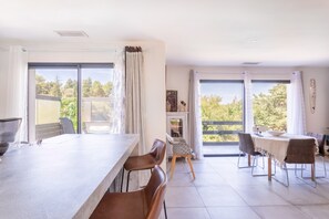 Une cuisine moderne avec un coin repas, de grandes fenêtres et une vue sur l’extérieur.