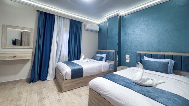A hotel room with two beds, a mirror, an air conditioning unit, and a ceiling light. - Pulse Pyramids Hotel (Giza)