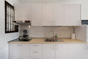 A modern kitchen with white cabinets, a stainless steel sink, and a built-in stove.