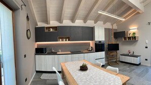 A modern kitchen with a wooden table and chairs, built-in appliances, and a pendant light.