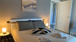 A neatly made bed with pillows, a bedside lamp, and a folded towel on the bed.