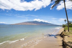 Una spiaggia con acque cristalline, una riva sabbiosa e una montagna all'orizzonte.
