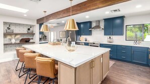 A modern kitchen with a large island, blue cabinets, and pendant lighting.