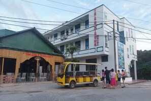 A yellow and white bus parked in front of a building with a sign that reads "Hainan Restaurant". - Thanh Trung Van Chay Hotel (Co To)