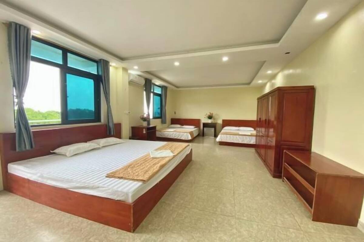 Hotellihuoneessa on suuri sänky, kaksi pienempää sänkyä, puinen vaatekaappi ja pieni pöytä.