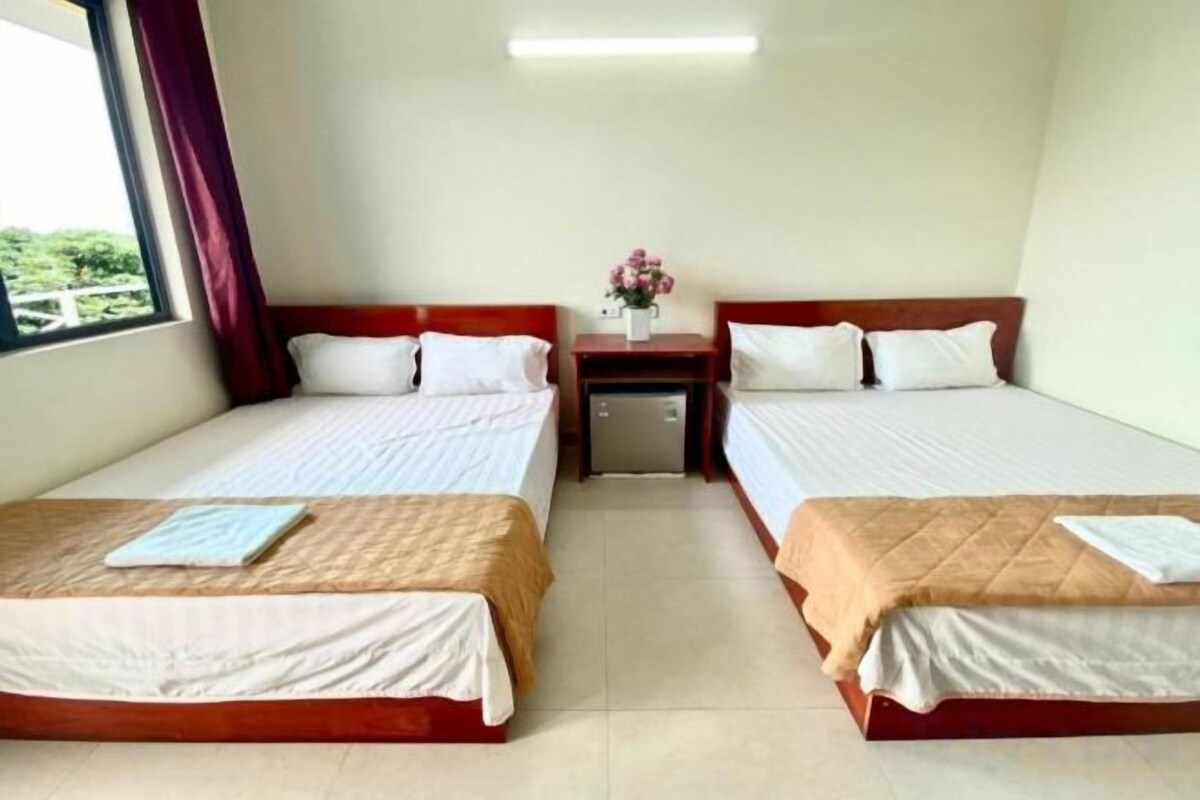 A hotel room with two beds, a nightstand, and a window with curtains.