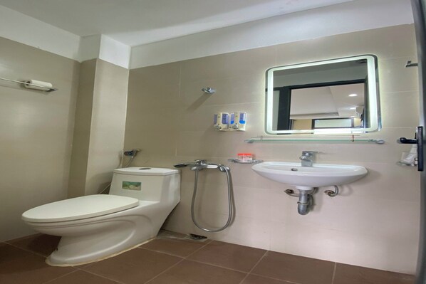 A bathroom with a toilet, a shower, and a sink.