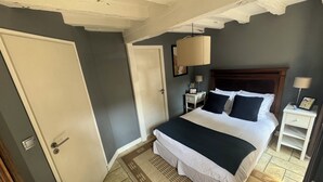 A bedroom with a bed, bedside tables, a nightstand, a lamp, and a door. - Idyllic Village Cottage With Hot Tub & Scenic Views (Mont-Saint-Jean)