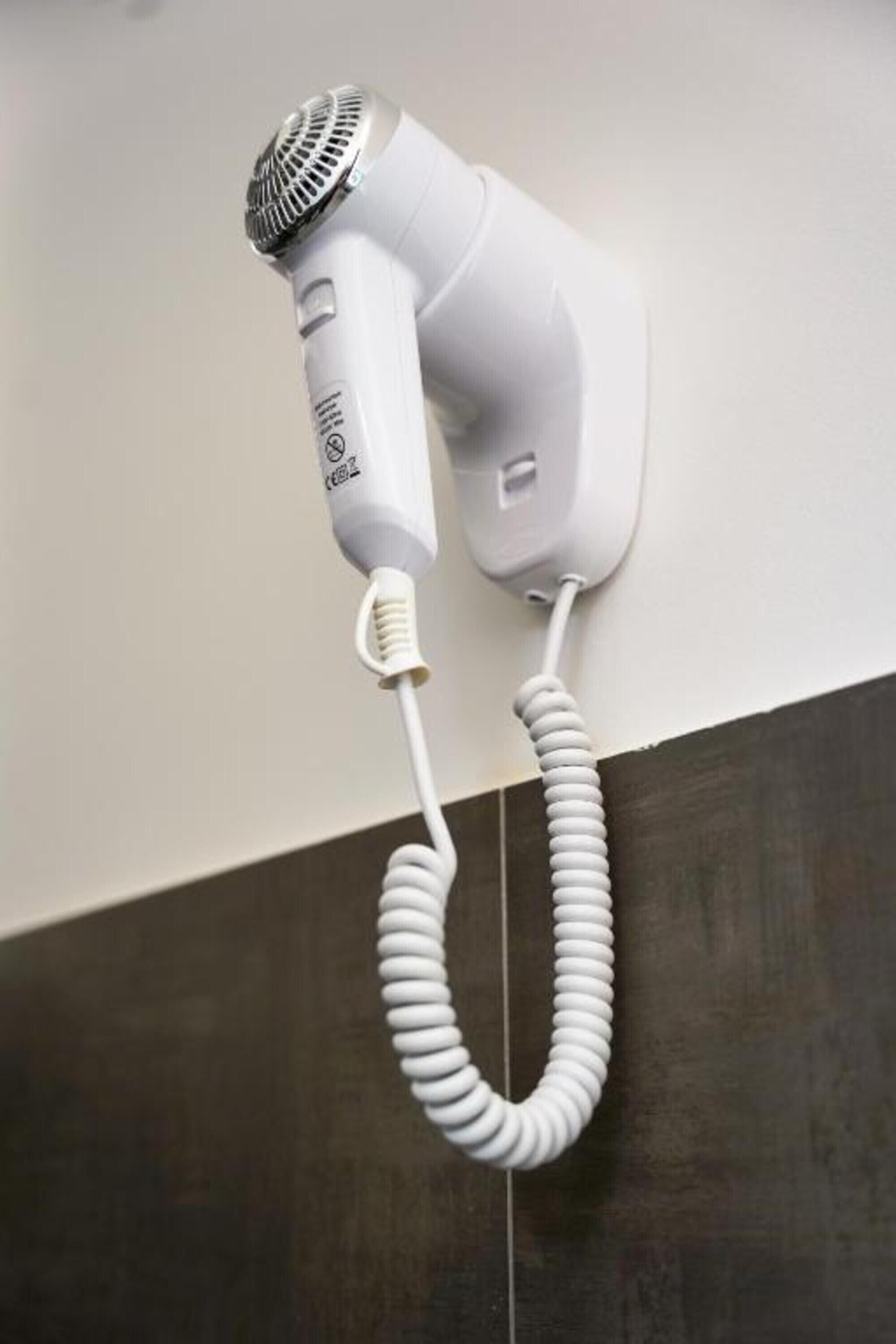 Ein an der Wand befestigter Haartrockner mit aufgewickeltem Kabel.