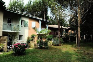 Un edificio residenziale con giardino, un balcone e un piccolo spazio patio.