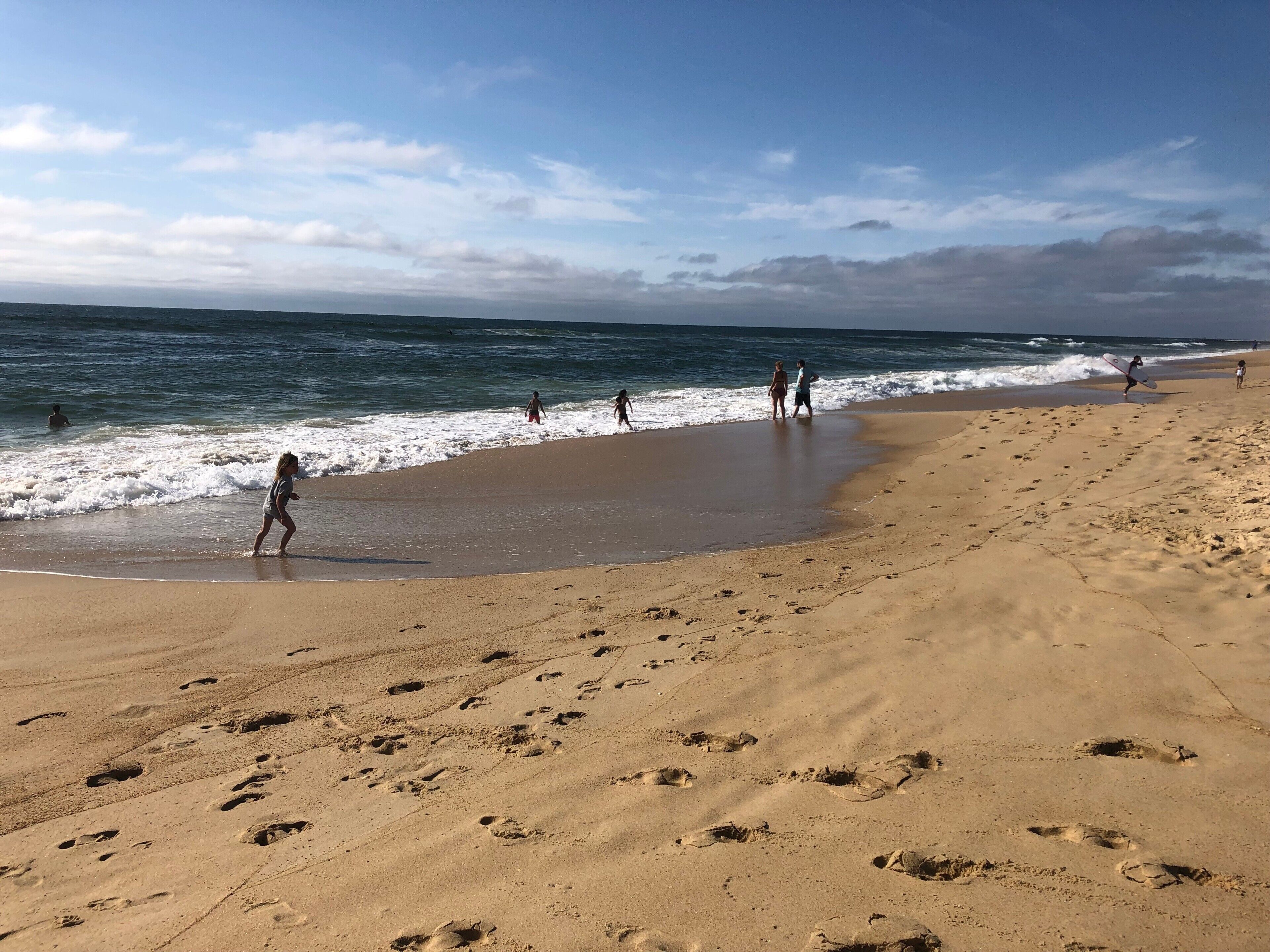 Een zandstrand met voetafdrukken, een heldere lucht en de oceaan.