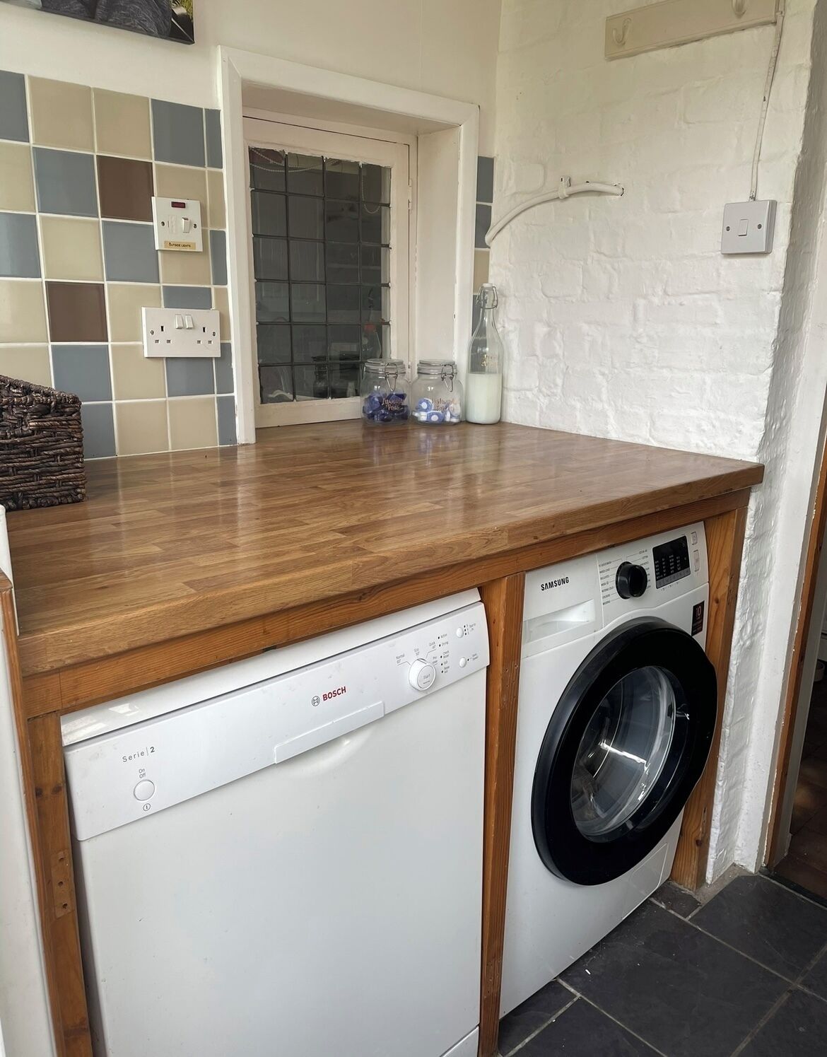 A compact kitchen with a Bosch dishwasher and a Samsung washing machine.