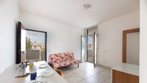 Una cocina moderna con comedor, sofá y puerta corrediza de vidrio que da a un patio exterior.