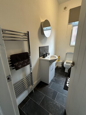 A compact bathroom with a towel rack, a sink, and a toilet.