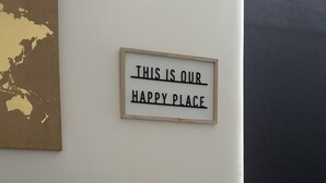 A dining area with a table set for a meal, a sign on the wall that reads "THIS IS OUR HAPPY PLACE", and a map on the wall. - Cosy Manchester House Near Etihad and Coop Live (Manchester)