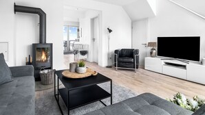 A modern living room with a fireplace, a flat-screen TV, a sofa, and a coffee table.