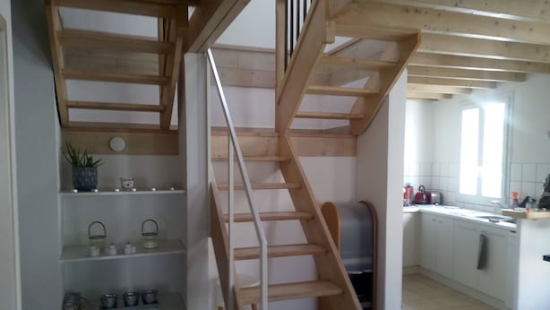 Een keuken met een houten trap naar een vide.